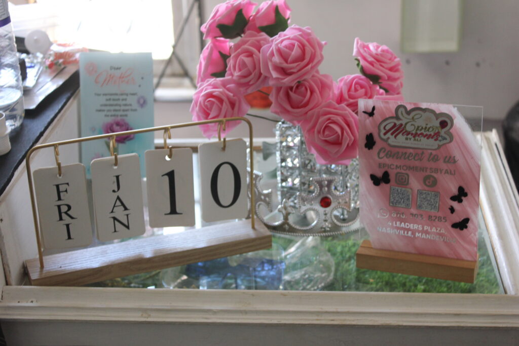 IMG_0721 Event display with pink roses, branded acrylic sign, and date cards.