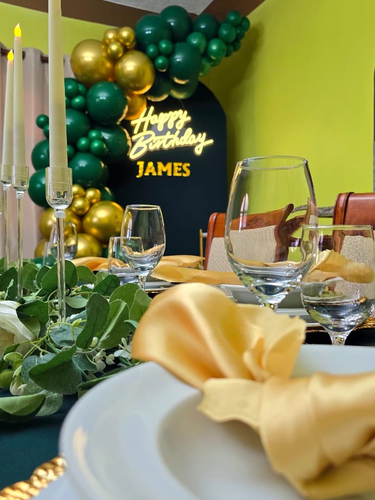 WhatsApp Image 2026-06-27 at 20.08.43 Close-up of green and gold birthday place setting with Happy Birthday James backdrop.